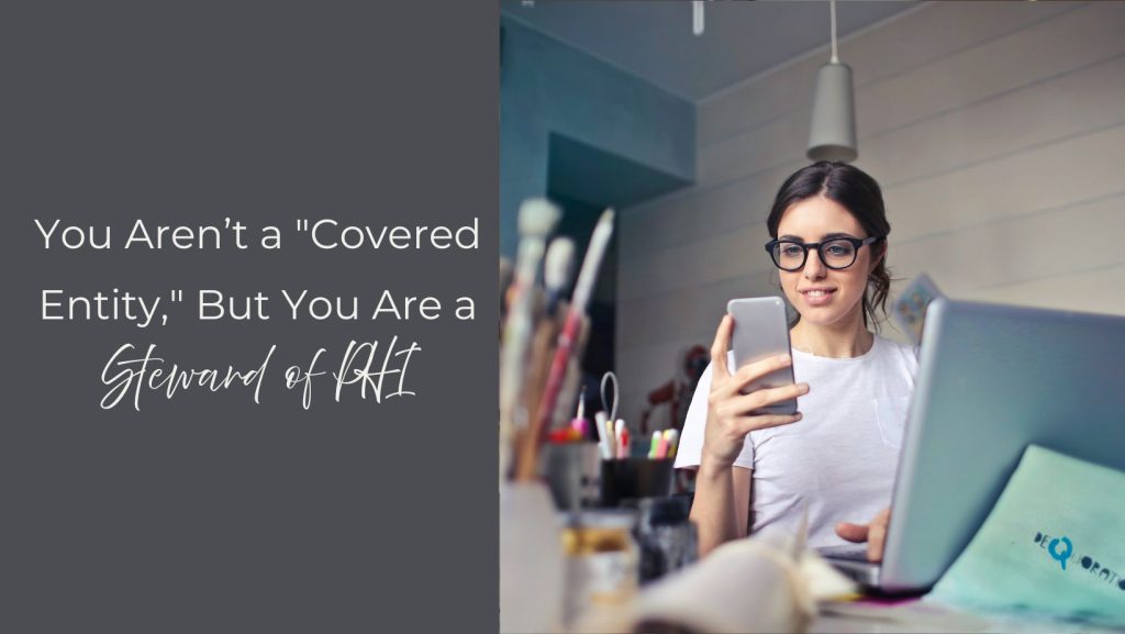 woman sitting at desk with laptop and cell phone in her hand